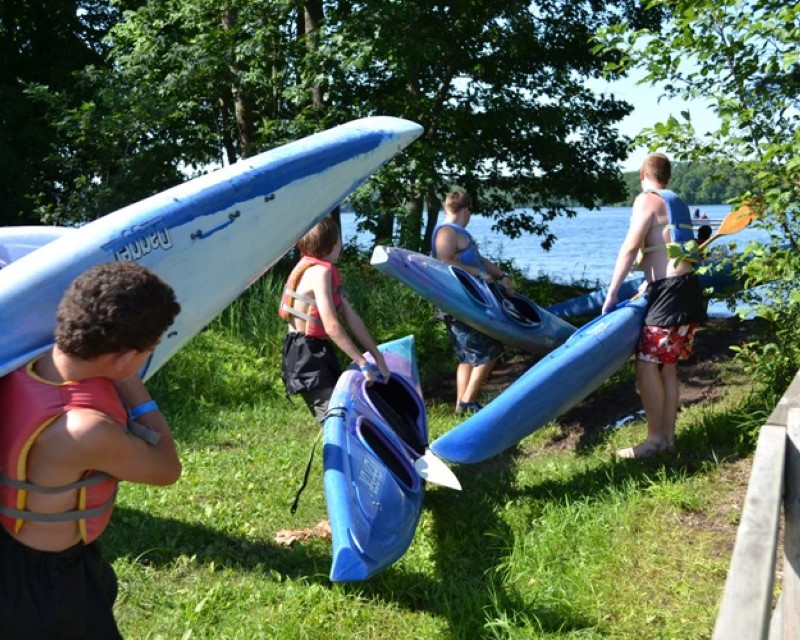 Four Scouts carrying kayaks towards the lake