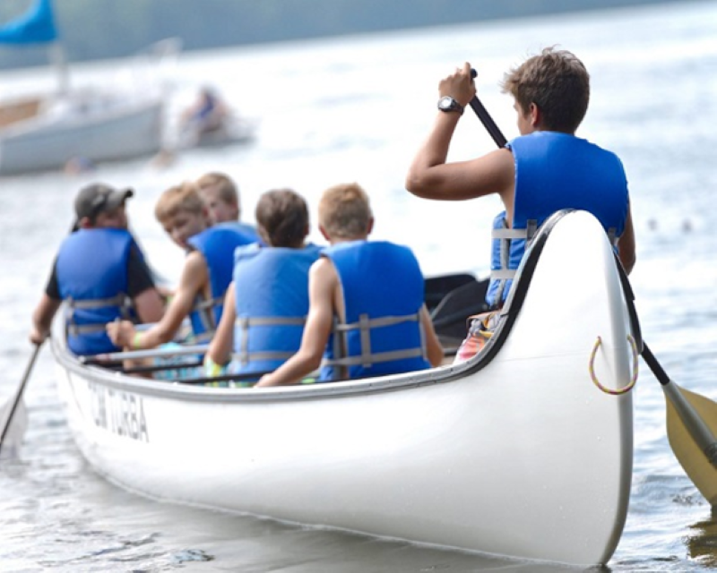 A group of Scouts canoeing in the voyageur canoe, a large canoe that seats 15 people