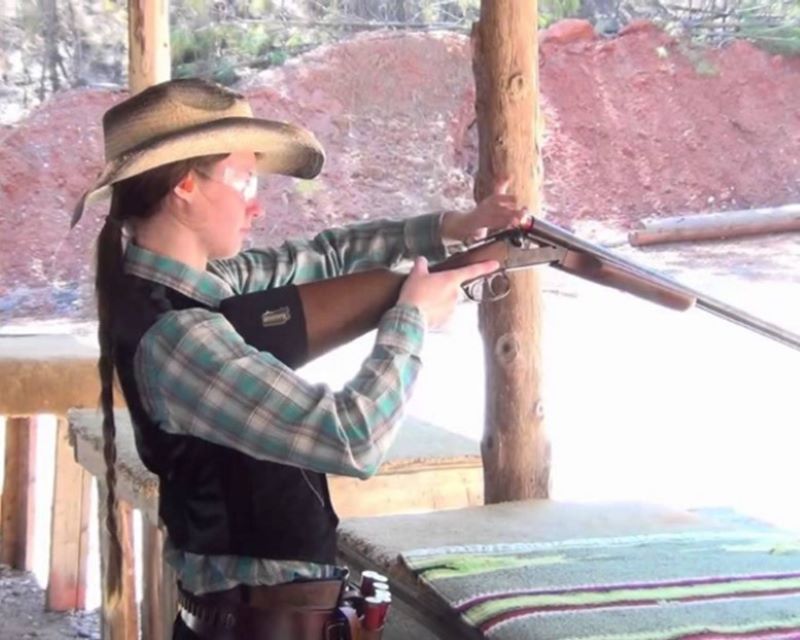 A flannel-clad shooter reloads her lever-action rifle